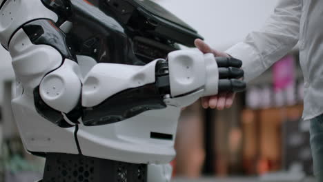 Moderne-Robotertechnologien.-Ein-Mann-Kommuniziert-Mit-Einem-Roboter-Und-Drückt-Einen-Mechanischen-Kunststoffarm-Auf-Den-Händedruck-Des-Roboters.