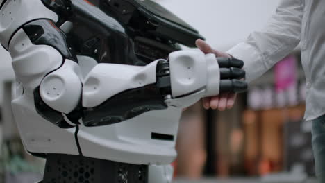 modern robotic technologies. a man communicates with a robot presses a plastic mechanical arm to the robot handshake.