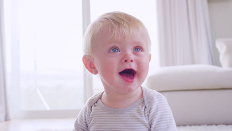 happy white toddler boy holding ball at home, close up