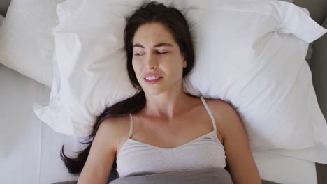 Confused-caucasian-woman-lying-in-bed-and-touching-her-head