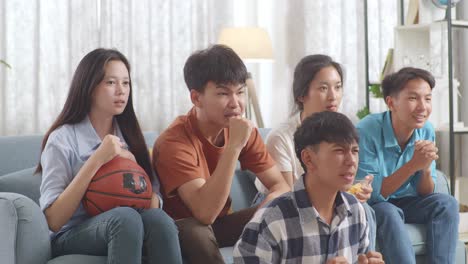 아시아 십대들이 스마트폰으로 농구 경기를 응원하고 지켜보고 있습니다. 팀은 승리를 축하하고 팀은 실망합니다.
