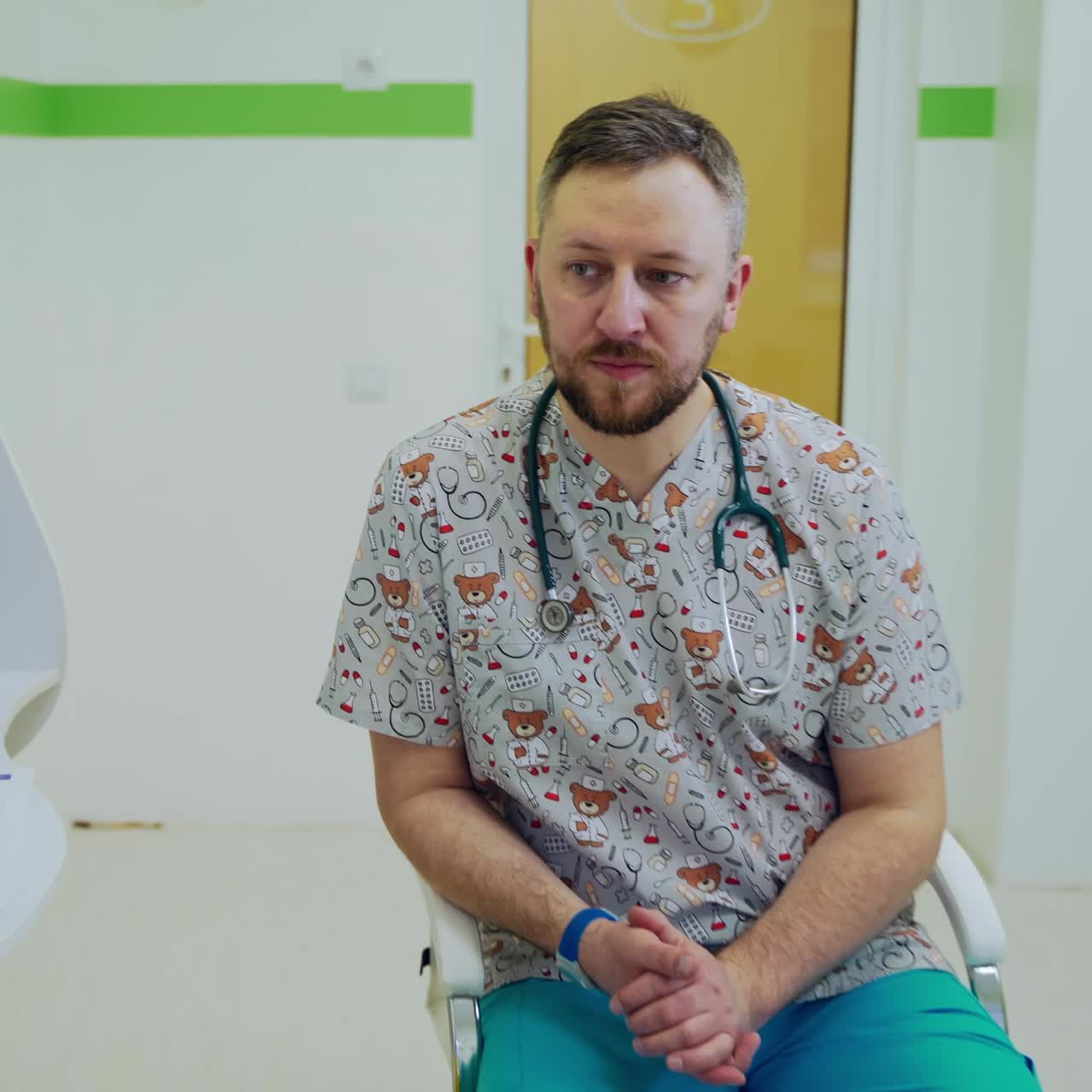 Medical consultation in kids center. Baby pediatrician talks to a woman sitting on a couch in clinic. Professional male doctor talks to a mother.