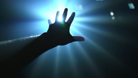 hand reaching out to cover shinning spot light