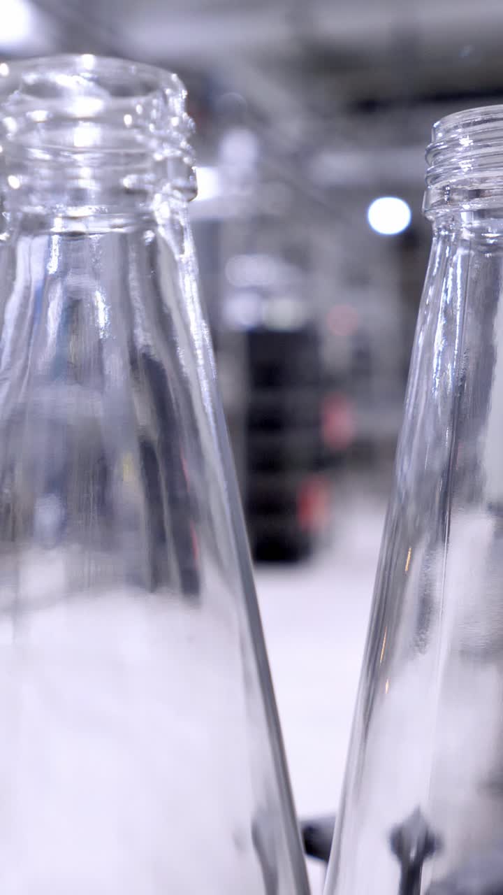 Glass bottles are arranged in a factory setting, showcasing the manufacturing process with blurred background elements and industrial ambiance for visual storytelling