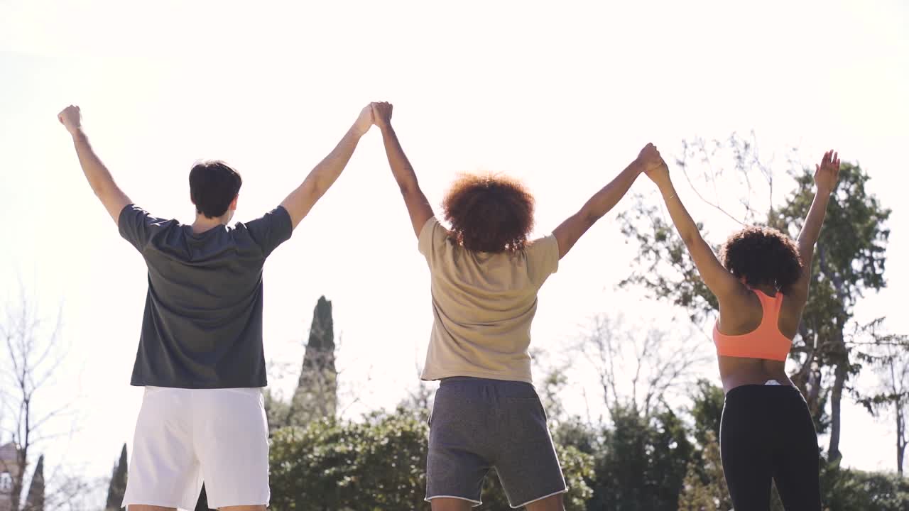 amigos alegres y diversos levantando los brazos en el parque
