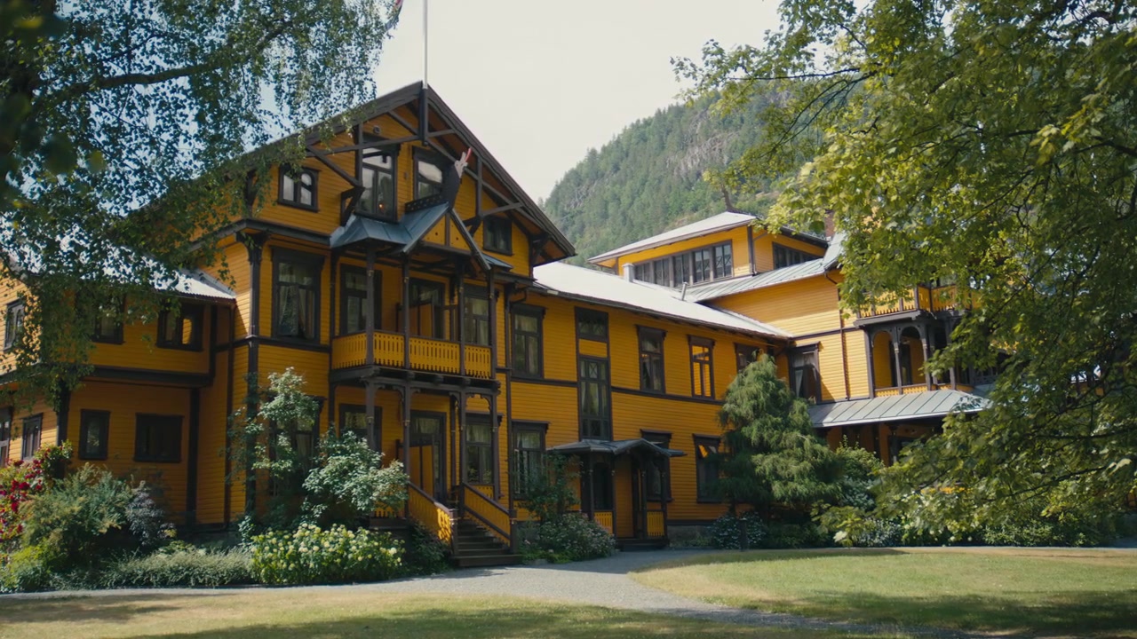 Historic timber hotel showcasing traditional dragon style architecture with decorative woodwork, steep gables and elegant Scandinavian craftsmanship surrounded by mature gardens.