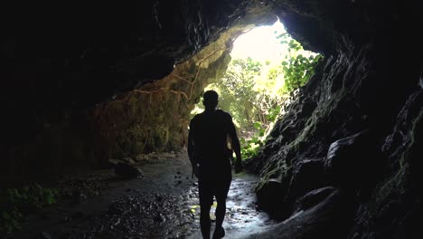 slowmo - young caucasian male walking through lava cave in new zealand