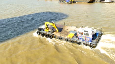 cargo ferry with yellow crane, traveling down the river thames - aerial view