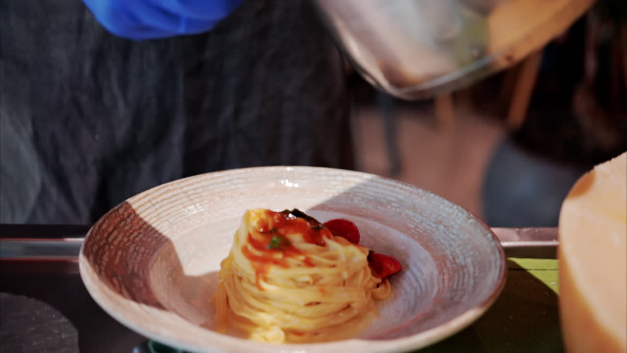 Man pouring sauce on pasta in a restaurant