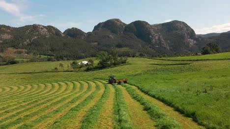 a tractor cutting grass for harvest in a field on a rural mountain farm