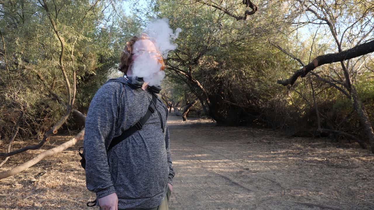 рыжеволосый мужчина, стоящий под деревьями.