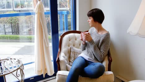 Woman-looking-through-window-while-having-coffee