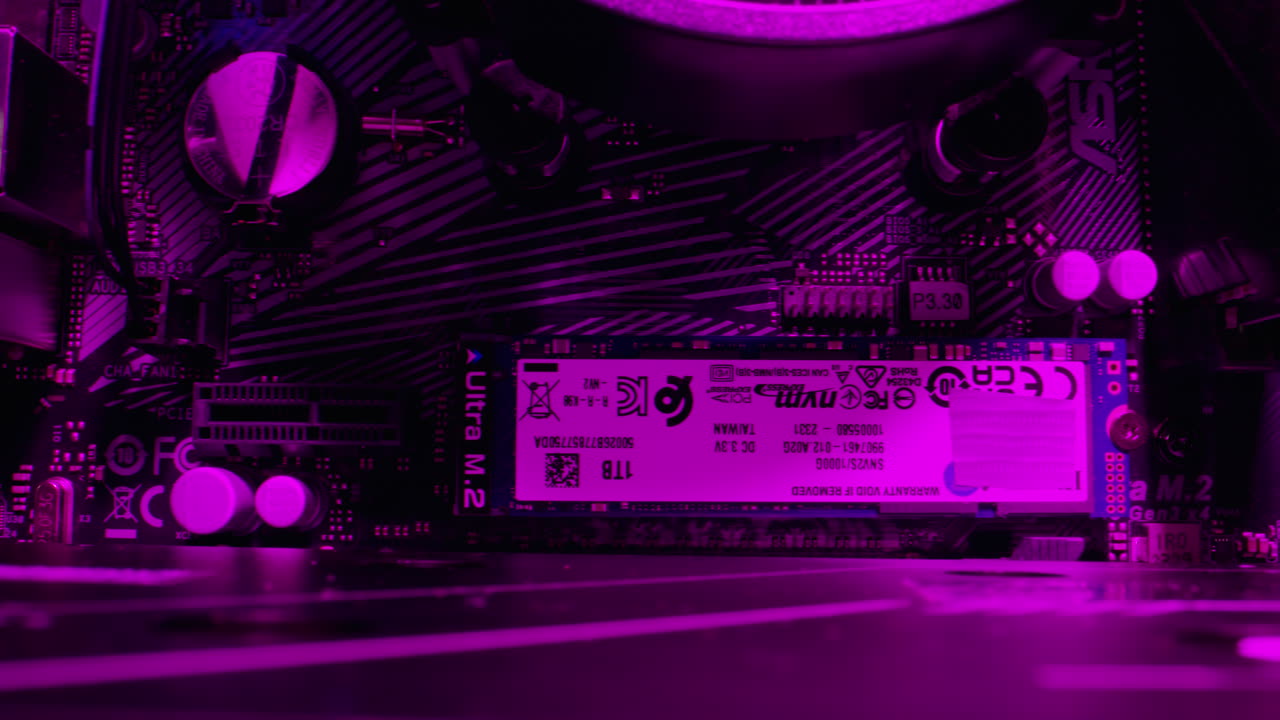 Close-up of a computer motherboard with an M.2 SSD in purple lighting