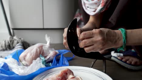 Aruvamanai,-a-traditional-vegetable-cutter,-is-utilized-to-slice-raw-chicken-meat,-demonstrating-the-artistry-of-meal-preparation-and-culinary-skills-in-cooking