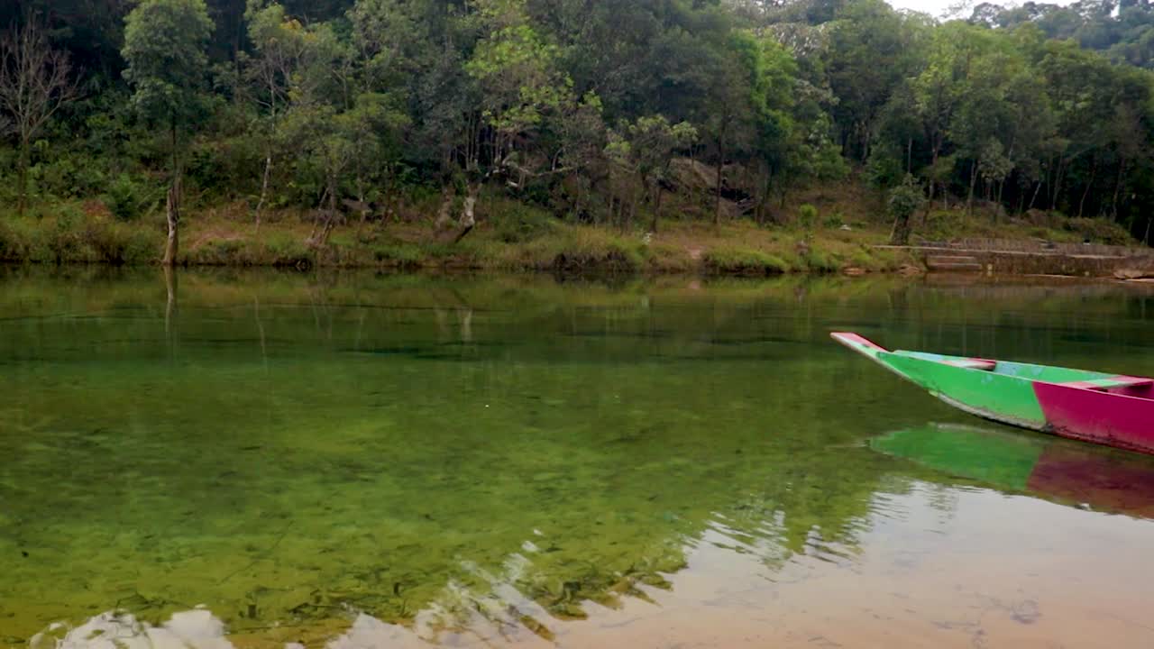 barco de madera tradicional en la orilla del río con bosques verdes por la mañana desde un ángulo plano