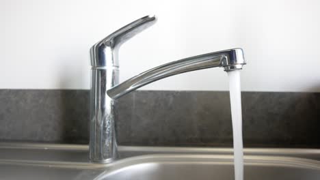 closeup of a chrome faucet with water running