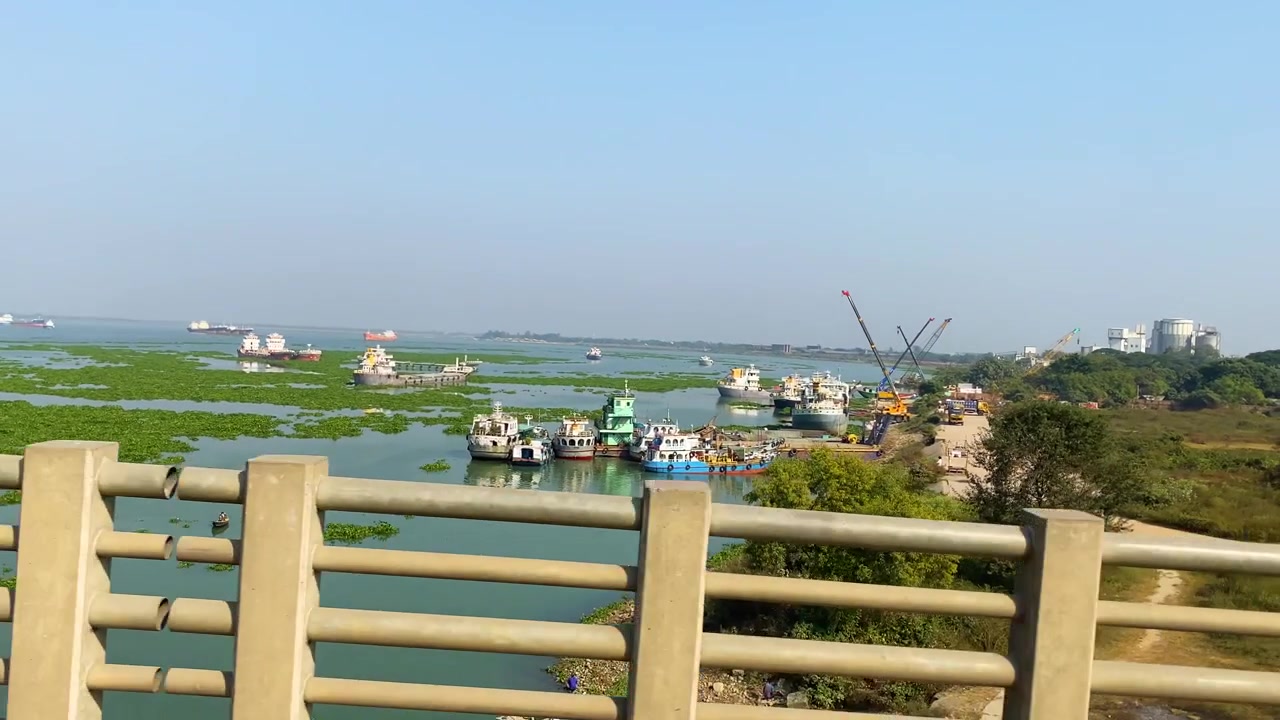 Nave da carico ormeggiata in un porto commerciale con un fiume tranquillo sotto un cielo velato in Bangladesh