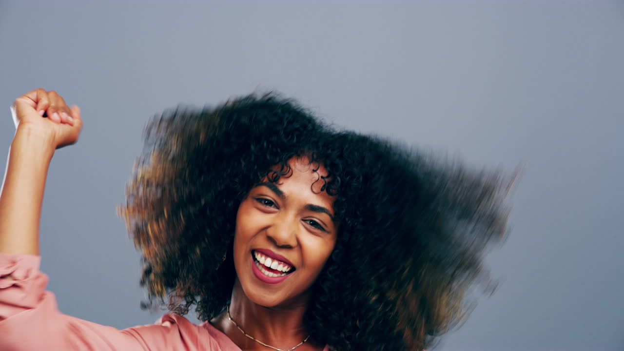 una mujer joven bailando contra un fondo gris