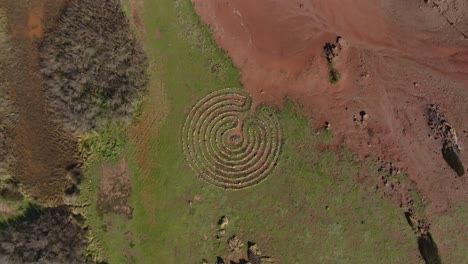 Swirling-therapeutic-rock-pattern-across-binimel-la-beach-menorca-spain,-rising-drone-spin