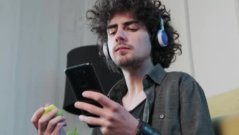 young man listening to the music and dancing while eatting an apple