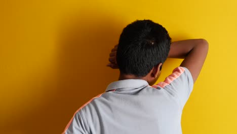 boy leaning against a yellow wall