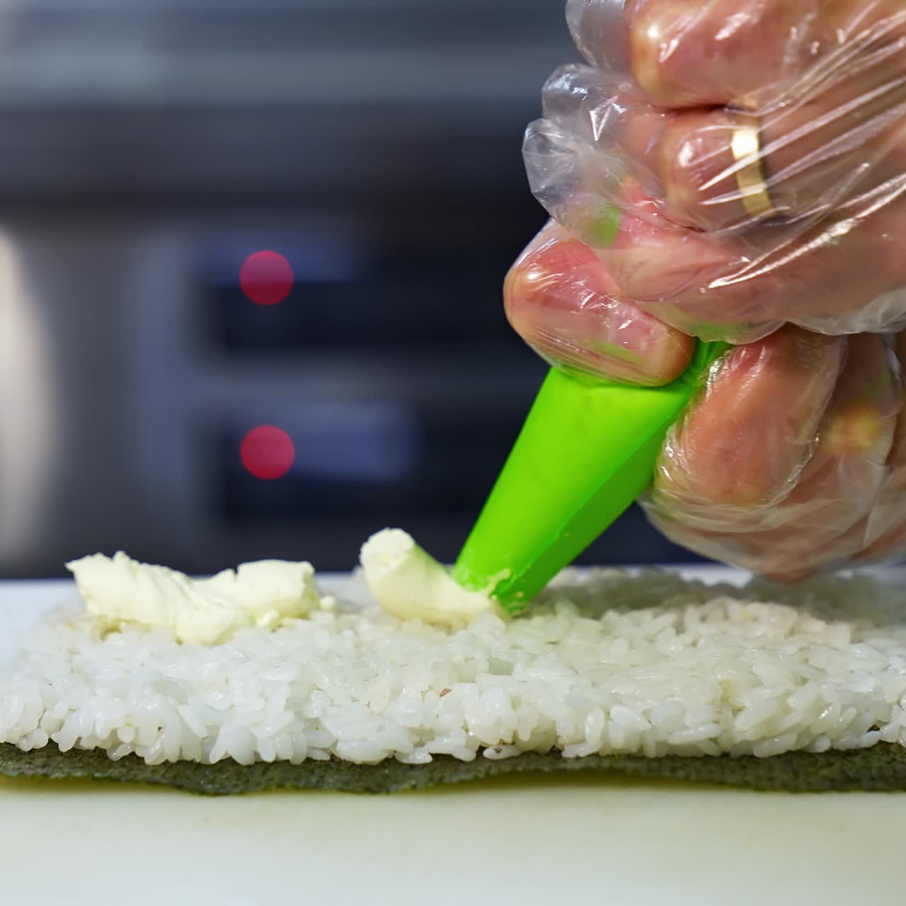 Chef in restaurant prepares sushi rolls with tasty ingredients. Cook`s hands putting cream cheese. Delicious asian food concept