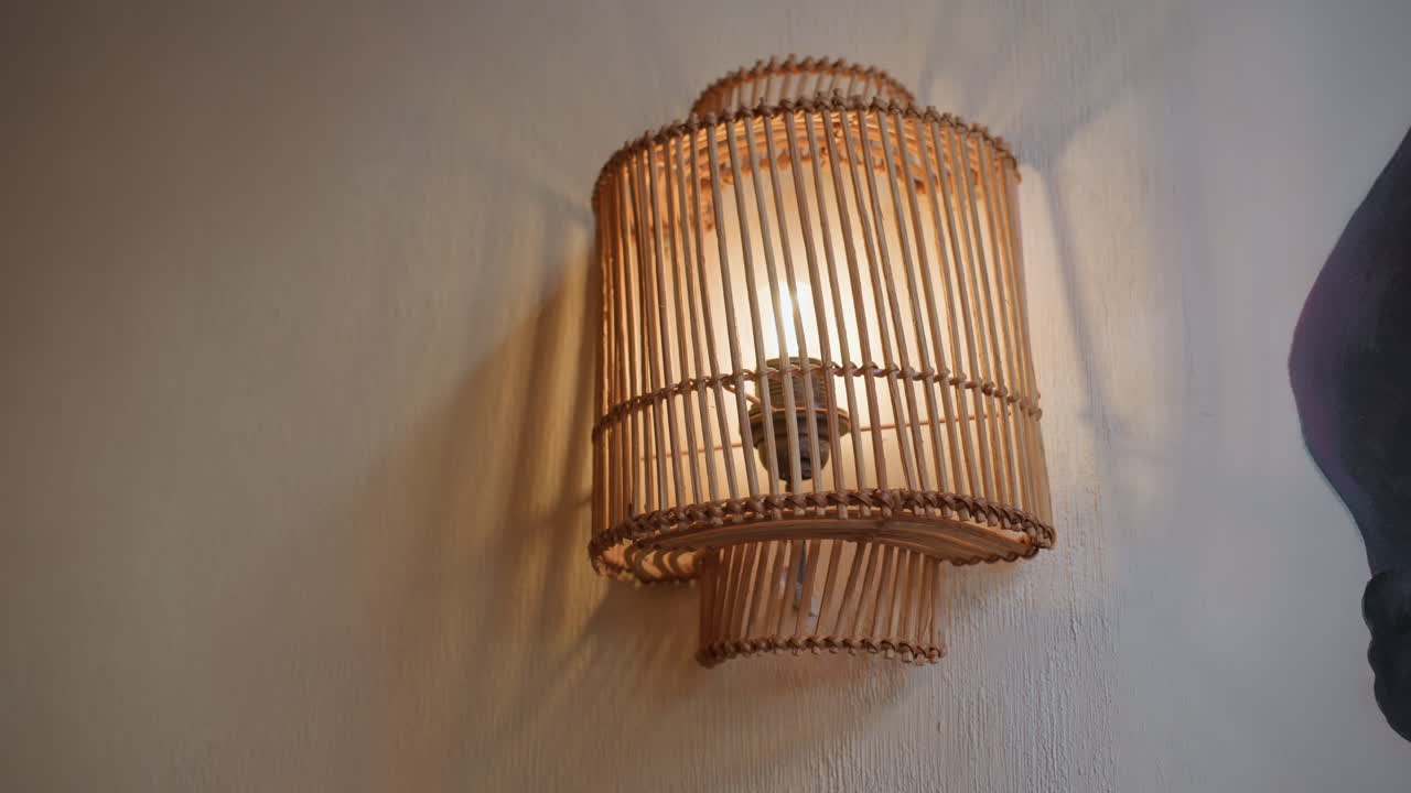 Beautiful view of light bulb glowing warmly inside vertically slatted wooden decorative frame mounted on textured wall, casting soft shadows and creating cozy ambient lighting