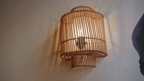 beautiful view of light bulb glowing warmly inside vertically slatted wooden decorative frame mounted on textured wall, casting soft shadows and creating cozy ambient lighting