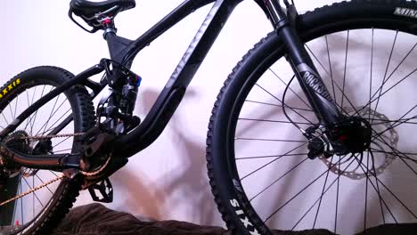 una panorámica lenta hacia arriba para revelar una bicicleta de montaña negra profesional con suspensión total y frenos de disco hidráulicos