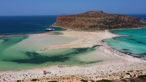 aerial panning across balos beach and lagoon with turquoise water, mountains and cliffs in crete, greece