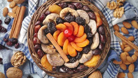 composition of dried fruits and nuts in small wicker bowl placed on stone table