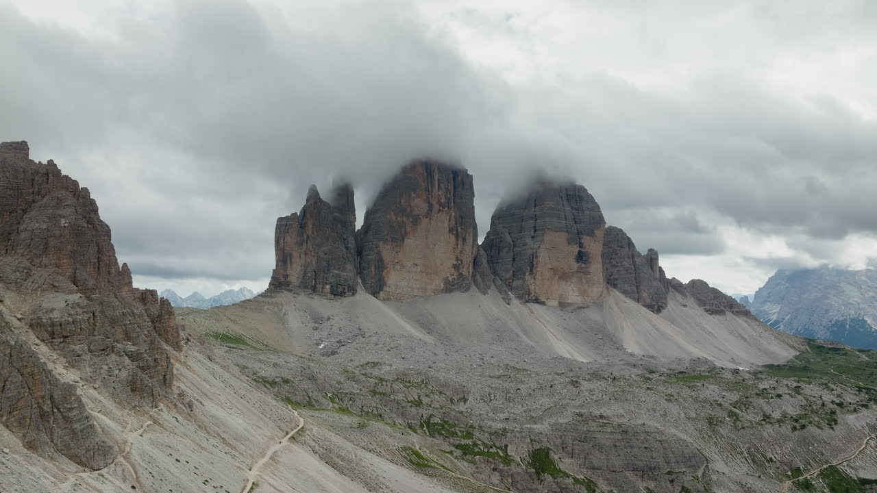 Tre Cime di Lavaredo or Three Peaks limestone face partially covered in clouds, Dolomites, Drone shot