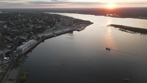 fotografía aérea de un buque de carga con contenedores navegando a través del río paraguay al atardecer en la bahía de asunción, puerto comercial