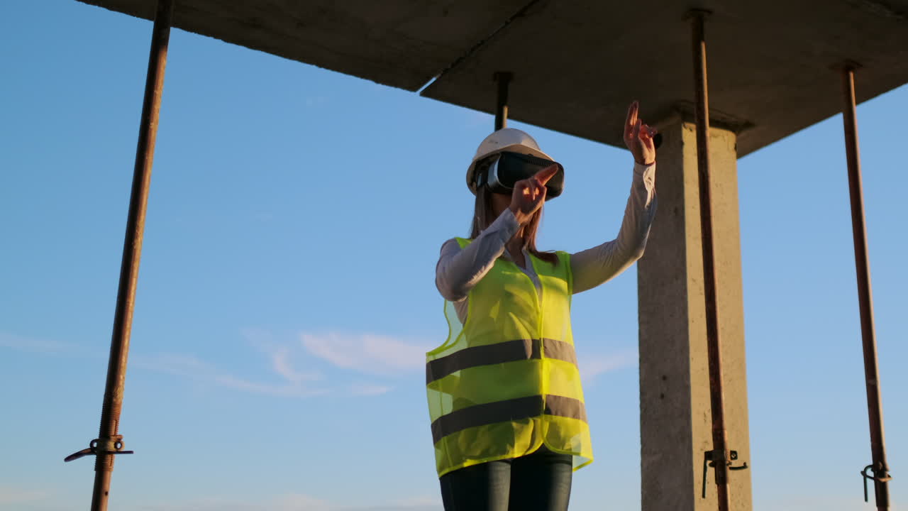 una mujer ingeniera en un sitio de construcción en gafas de realidad virtual mueve sus manos simulando el trabajo de la interfaz del futuro al atardecer