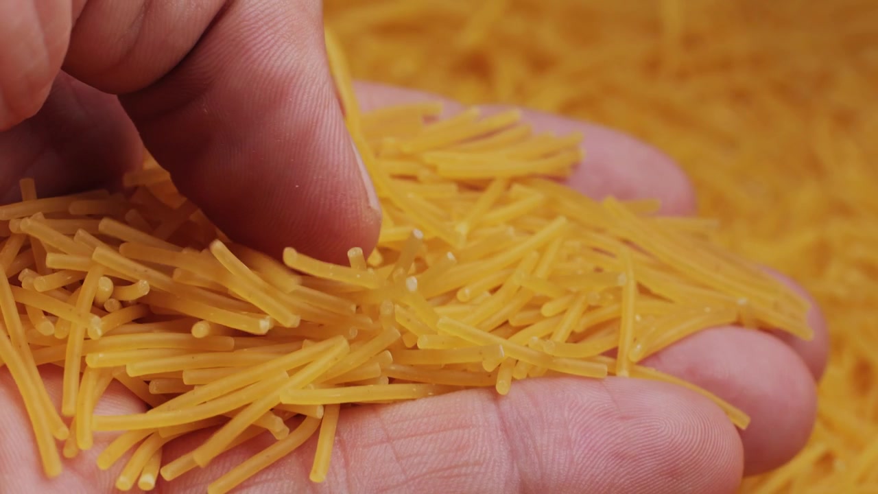 Primer plano de mano vertiendo pasta vermicelli seca