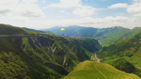 cinematic drone shot of a paraglider flying in the mountains in gudauri georgia