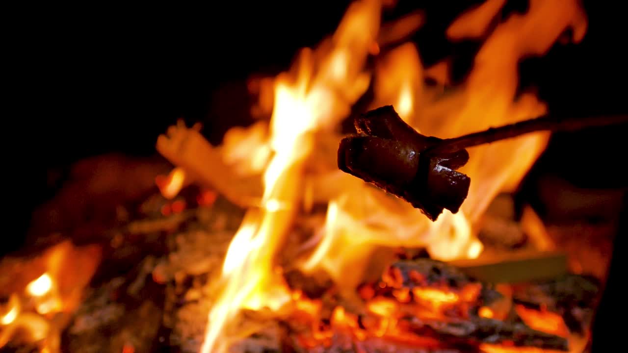 salchicha en un palo sobre el fuego