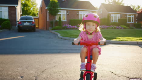 young girl riding a bike with a pink helmet