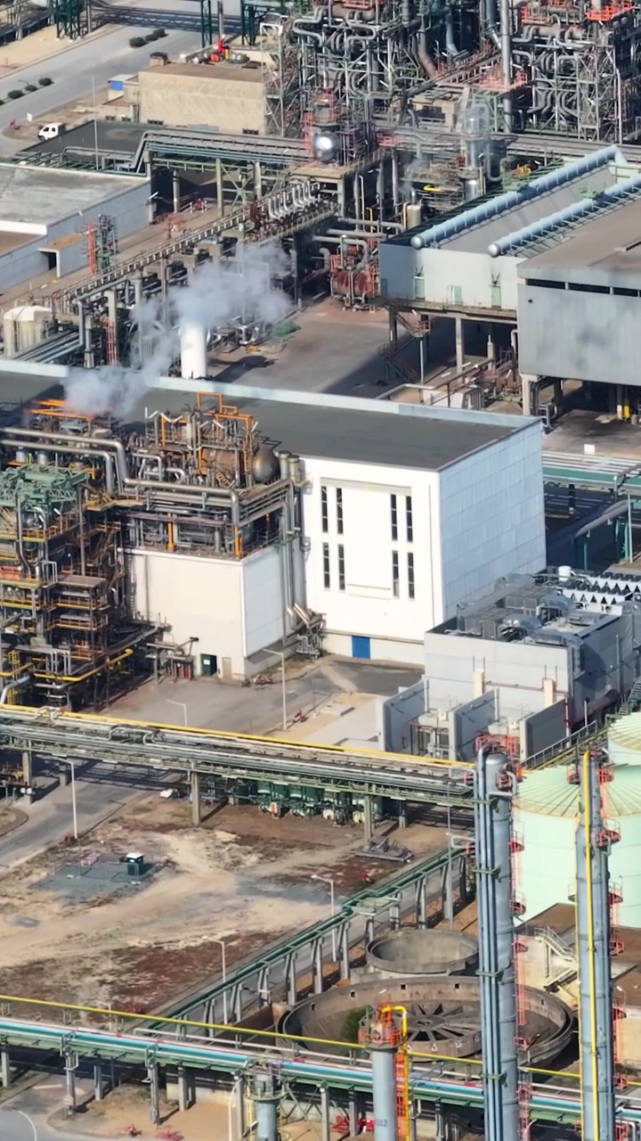 An oil refinery complex situated in an industrial processing area. The video shows multiple facilities and active operations within the petroleum production sector.