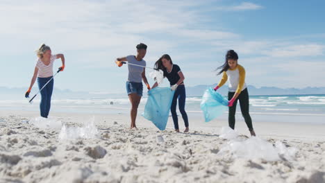 diverse group of female friends putting rubbish in refuse sacks at the beach