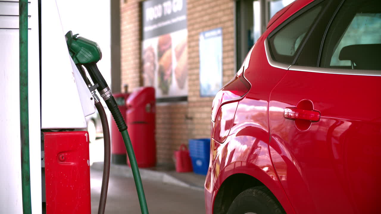 hombre llenando de combustible un coche en una gasolinera