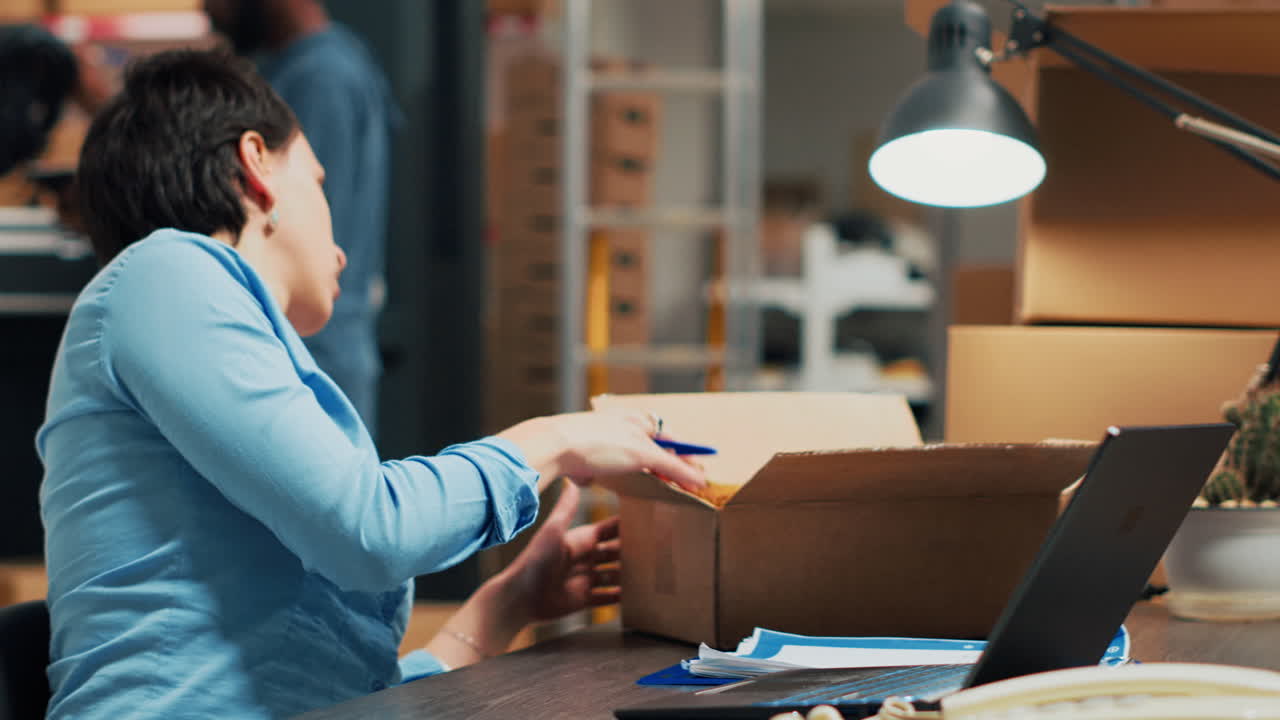 Woman working on laptop in office with boxes