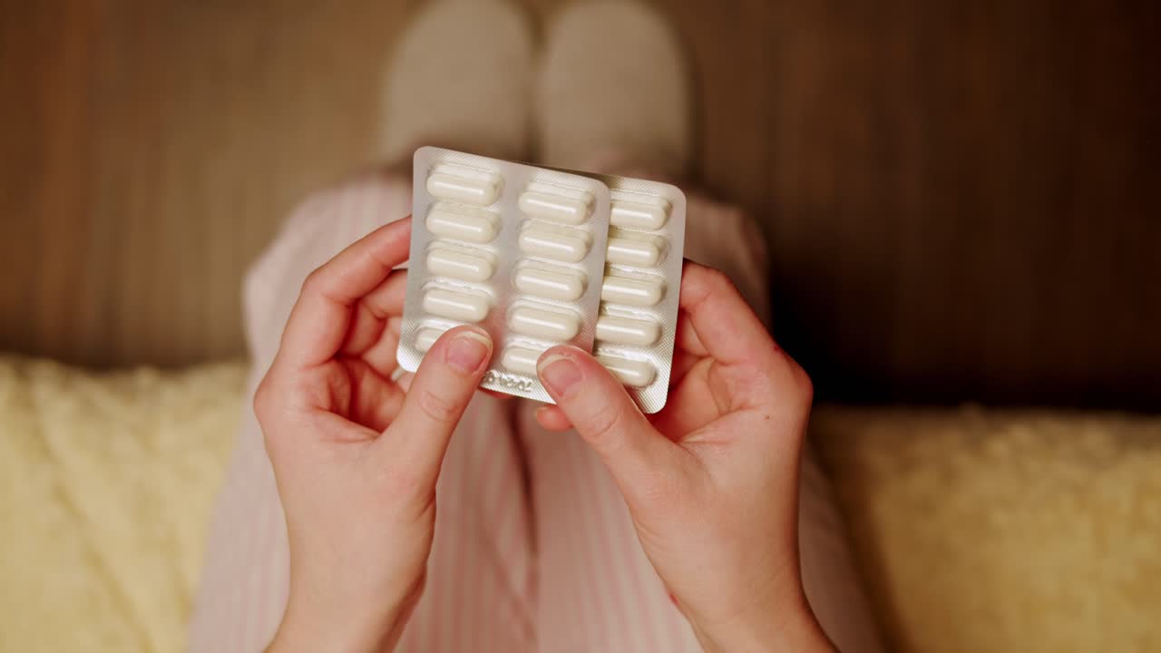 약 을 담은 블리스터 패키지 를 들고 있는 여자