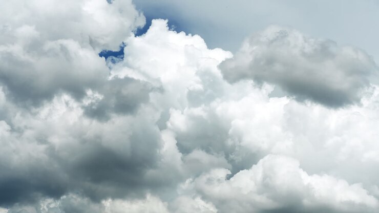Cumulus clouds move against a clear blue sky