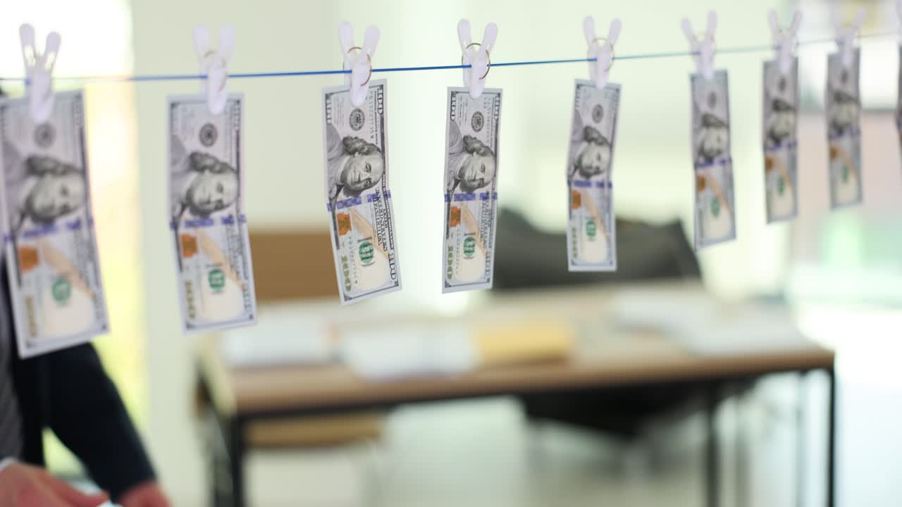 Businessman drying dollar bills on a clothesline, symbolizing money laundering