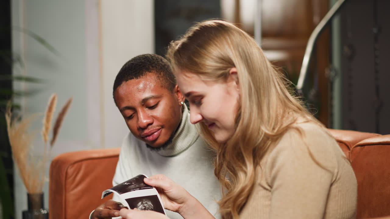 Family of woman and black man looks at ultrasonic photos