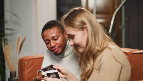 family of woman and black man looks at ultrasonic photos