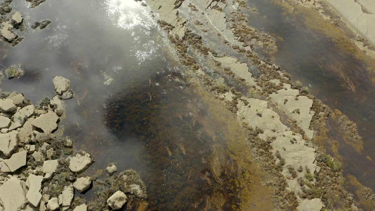 Sky reflections on natural pools teeming with marine life, creating a captivating opening shot