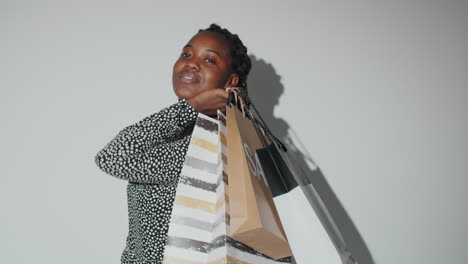 alegre mujer afroamericana sosteniendo bolsas de compras y posando para la cámara