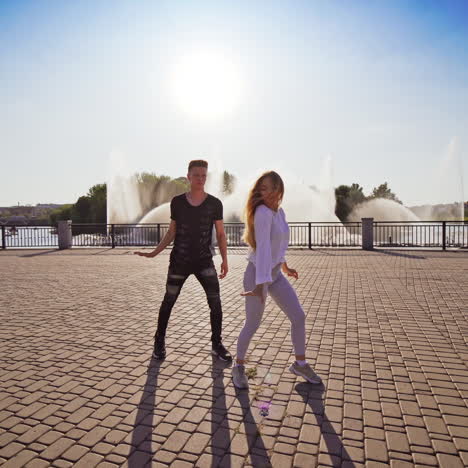 man and woman dancing outdoors. young couple moving synchronously in the street. boy in black and girl in white perform beautiful dance.